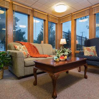A cozy living room with ample natural light, featuring comfortable furniture and a touch of greenery.