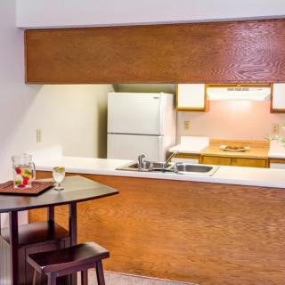 A cozy kitchen interior with a counter, refrigerator, and small dining area.