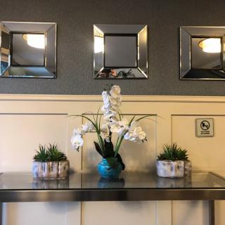 A stylish interior display featuring a floral arrangement, modern mirrors, and decorative plants.