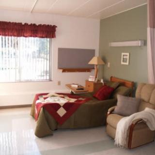 A comfortable hospital room with a bed, armchair, and window.