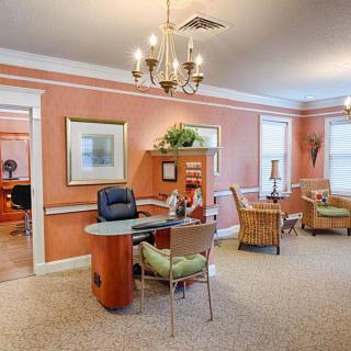 A warmly decorated office space with a central desk and seating area, adorned with artwork and light fixtures.