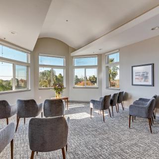 A bright meeting room with chairs arranged in rows and large windows providing a scenic view.