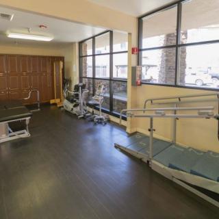 A rehabilitation center with exercise equipment and parallel bars for physical therapy.