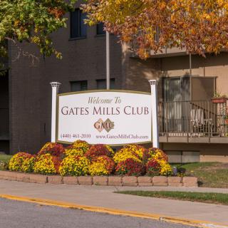Sign for Gates Mills Club surrounded by autumn foliage and flowers.