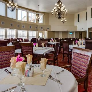 An elegant dining room with neatly arranged tables and chandeliers.