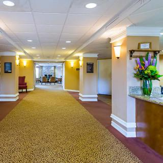 A well-lit lobby interior with a carpeted hallway and floral arrangement.