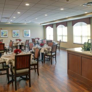 A well-lit dining area with neatly arranged tables and chairs, featuring elegant decor.