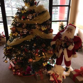 A decorated Christmas tree with presents underneath and a Santa Claus figure nearby.