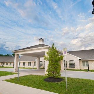 A healthcare facility with a covered entrance and manicured lawn under a cloudy sky.