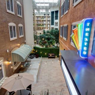 View of an indoor atrium with a neon sign and greenery.