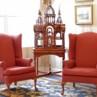 A pair of red wingback chairs flanking an ornate wooden cabinet in a classic interior setting.