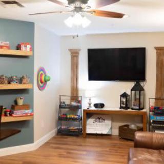 A cozy living room featuring a wall-mounted TV, stylish shelves, and elegant decor.