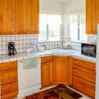 A cozy kitchen with wooden cabinets and a tile backsplash, featuring countertop appliances like a coffee maker and microwave.