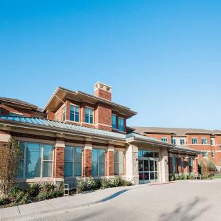 A modern brick building with large windows and a clear blue sky overhead.