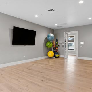 A spacious and modern room featuring a mounted television, exercise balls, and a minimalist design.