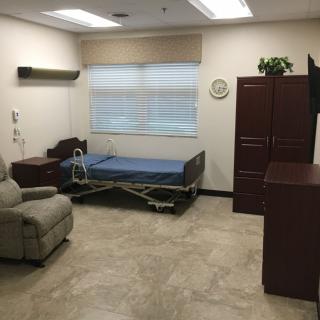 A hospital room featuring a bed, recliner, and storage cabinets.