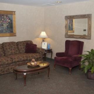 A cozy living room with a patterned sofa, burgundy armchair, and a central coffee table under soft lighting.