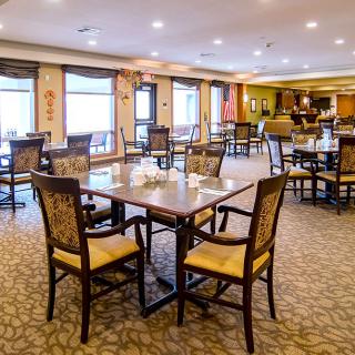 A spacious dining area with neatly arranged tables and chairs, featuring warm lighting and elegant decor.