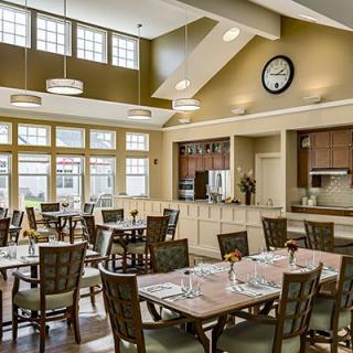 A modern and spacious dining area with neatly arranged tables, ample natural light, and elegant lighting fixtures.