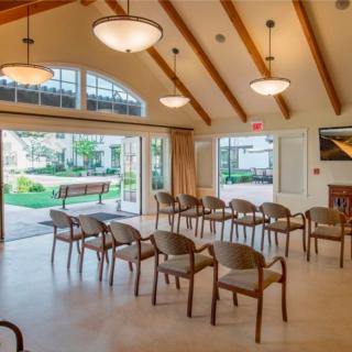 A bright and spacious meeting room with chairs arranged in rows facing large windows and a garden view.