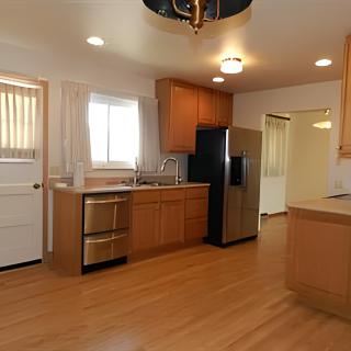 A modern kitchen with wood flooring, stainless steel appliances, and ample cabinetry.