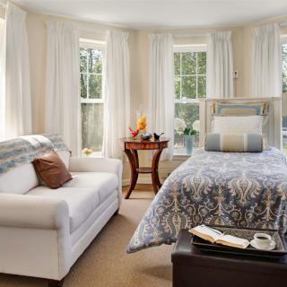 A cozy bedroom with large windows, a comfortable bed, and a plush sofa.