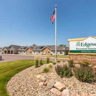 A view of an exterior facility with a prominent sign and flagpole, surrounded by well-maintained landscaping.