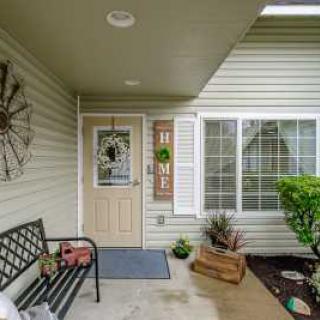 A welcoming front porch featuring a bench, potted plants, and decorative elements around the door.