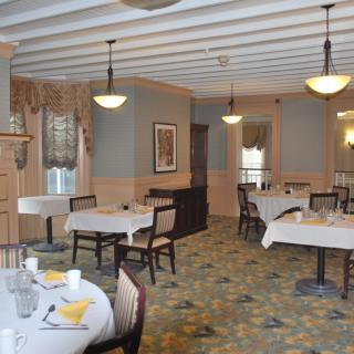 A cozy restaurant dining room with neatly arranged tables and warm lighting.