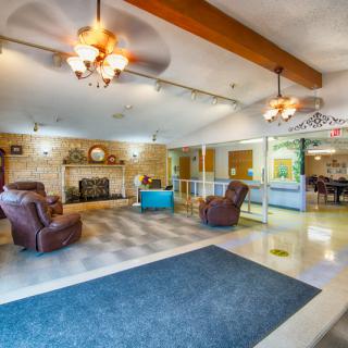 A spacious and well-lit lobby area with comfortable seating, a fireplace, and ceiling fans.