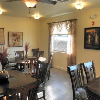 A cozy dining area featuring wooden furniture, decorative artwork on the walls, and ample natural light.