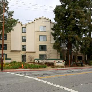 A residential building located by a street with trees and a sidewalk.
