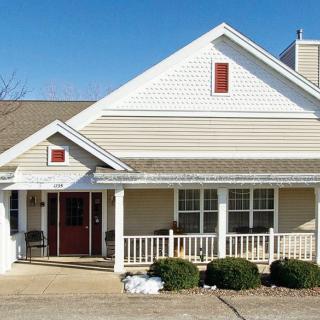 A suburban residential house with a front porch and neatly trimmed bushes.