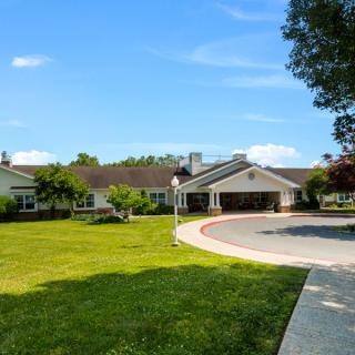 A spacious residential house with a large lawn and driveway under a clear blue sky.