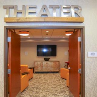 An entrance to a theater with a modern lounge area featuring cozy seating and contemporary design.
