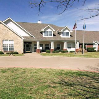 A residential building with a well-maintained lawn and flags at the entrance.