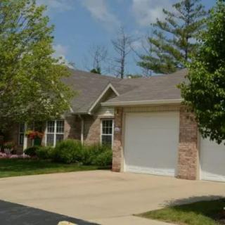 A suburban house with a garage and driveway surrounded by trees.
