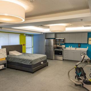 A modern room featuring a bed and integrated kitchen area.