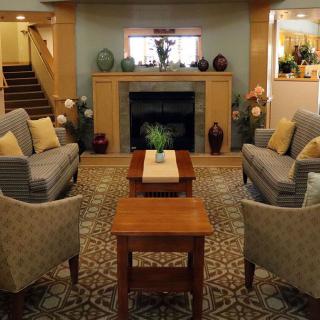 A cozy living room with a fireplace, sofas, and armchairs arranged around a coffee table.