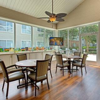 A modern dining area with tables and chairs, featuring large windows and abundant natural light.
