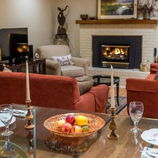 A cozy living room with a fireplace and comfortable seating, featuring a dining table set with candles and a fruit bowl.