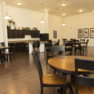 Spacious dining area with a connected kitchen, featuring wooden tables and chairs.