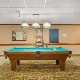 A billiards table in a warmly lit game room with artwork on the walls.