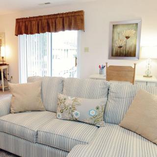 A cozy living room featuring a striped sofa adorned with decorative cushions, soft lighting, and wall art.