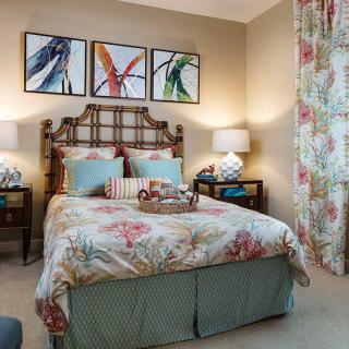 A stylish bedroom featuring floral patterns and colorful artwork above the bed.