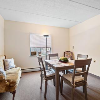 A cozy dining room with a wooden table, chairs, and a sofa by the window.