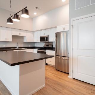 A modern kitchen featuring a central island, stainless steel appliances, and minimalist lighting.