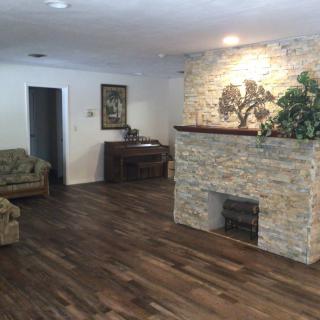 A cozy living room with a stone fireplace and hardwood floors.