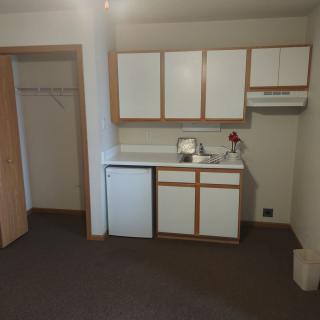 A minimalist kitchenette with white cabinets and a mini fridge.