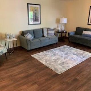 A cozy living room with comfortable seating, artwork on the wall, and a soft rug on a wooden floor.
